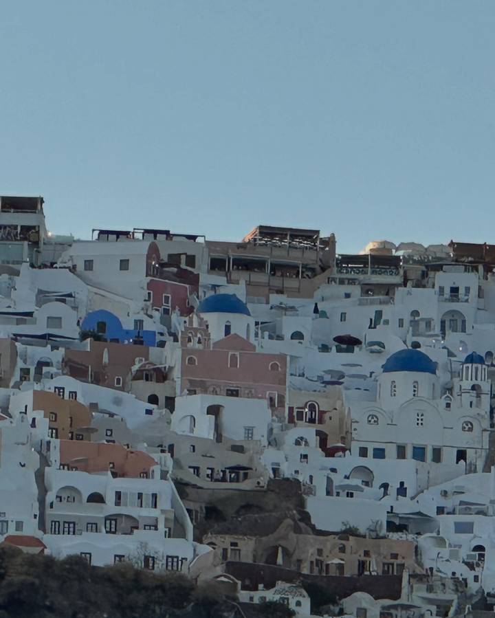 Whitewashed houses and blue-domed churches clustered on a Santorini cliffside.