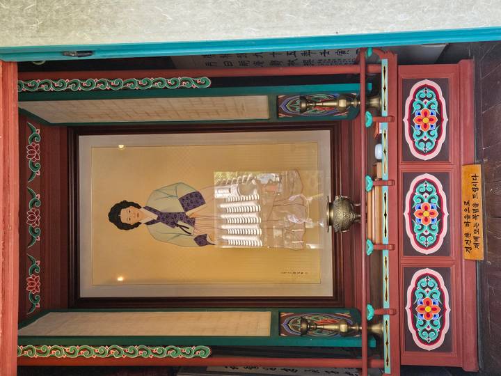 Framed portrait of a woman in traditional dress displayed inside an ornate wooden shrine.