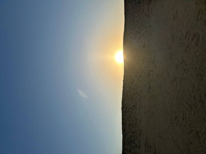 Rising sun just above a low sandy ridge in the desert creating a soft glow