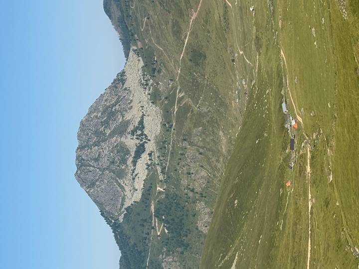 Isolated mountain peak rises above rolling green hills under a flawless blue sky.