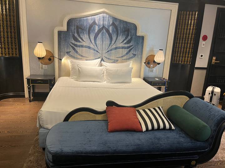 A stylish hotel room featuring a lotus-themed headboard, crisp white bedding and colourful accent cushions.