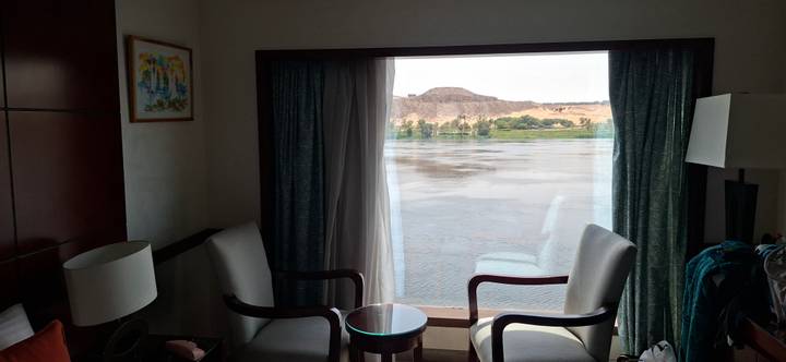 Cruise cabin sitting area with two chairs facing a large window overlooking the Nile River.