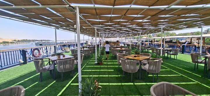 Open-air dining deck on a Nile cruise ship with green turf flooring and river views.