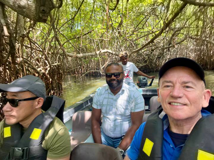 Tourists wearing life vests in a small motorboat navigating dense mangrove channels