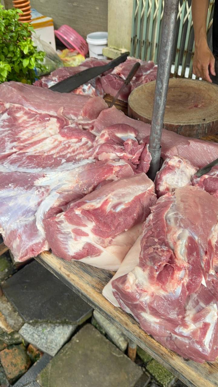 Close shot of raw cuts of pink meat displayed on a market table.