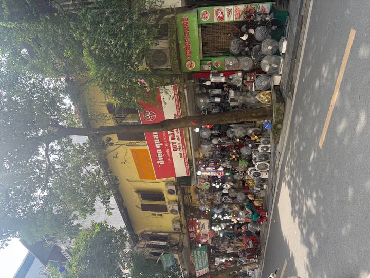 Street shop displaying a large assortment of electric fans outside a yellow colonial building.