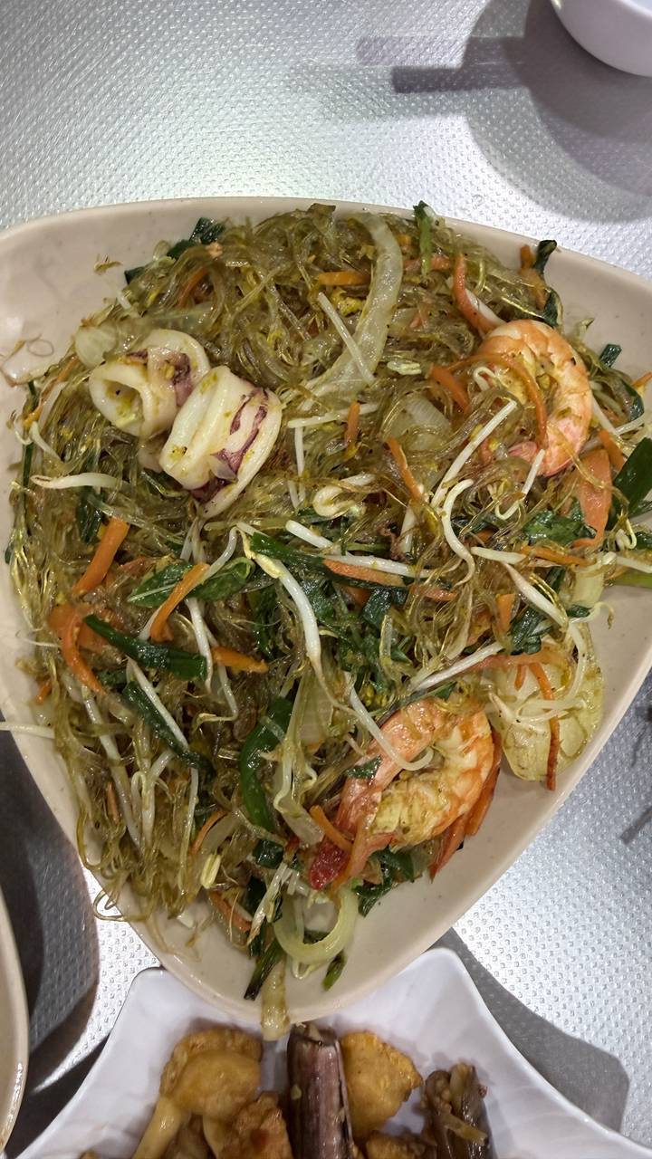 Close-up of stir-fried glass noodles with prawns, squid, bean sprouts and vegetables.