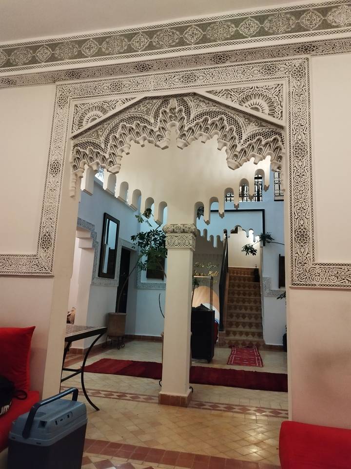 Ornate white stucco arches and detailed Moorish patterns inside a Moroccan riad.