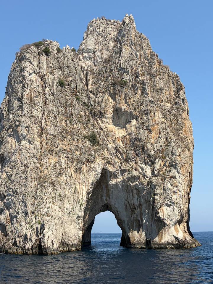 Towering limestone sea stack rising from deep blue Mediterranean waters off Capri.