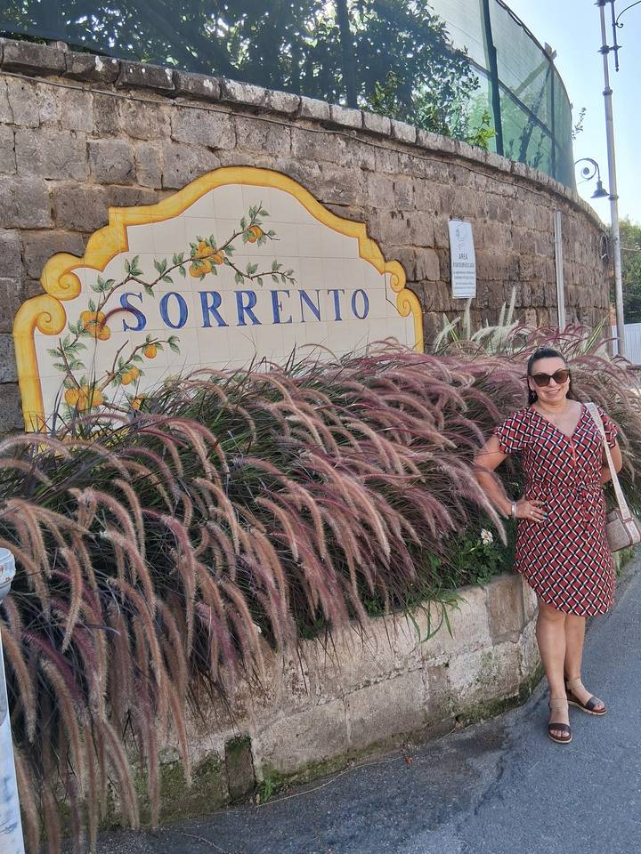 Woman posing beside a decorative ceramic Sorrento sign framed by ornamental grasses