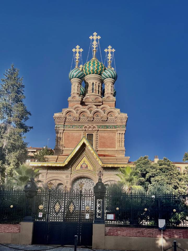 Colorful Russian Orthodox church with green onion domes and ornate brickwork against blue sky