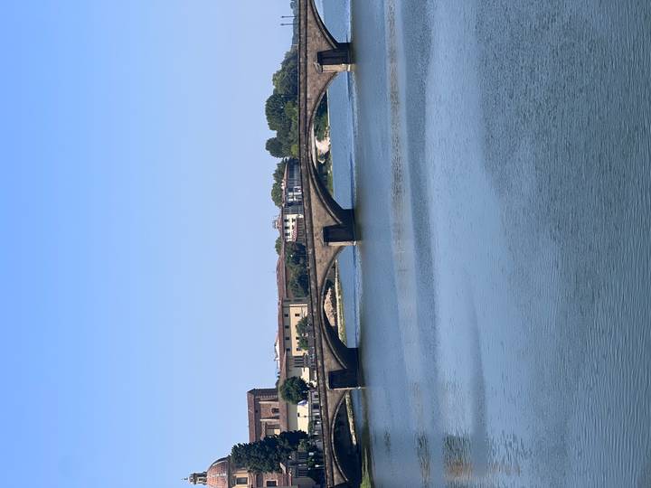 Stone arch bridge spanning a calm river under clear blue sky