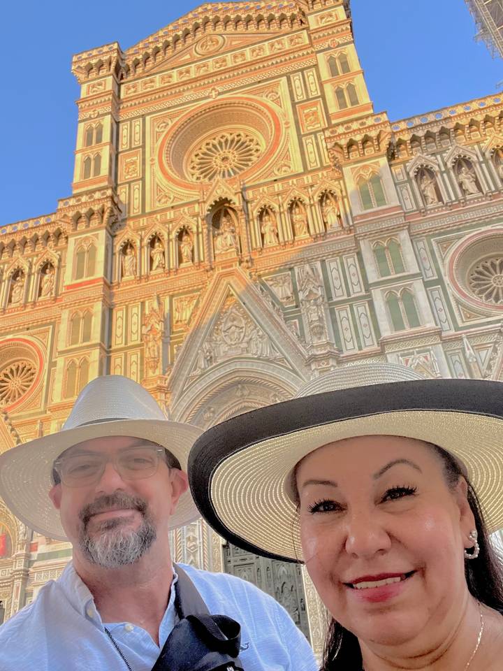 Selfie of couple in hats partly cutting off faces with Florence Cathedral facade behind