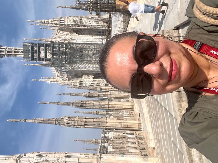 Woman taking selfie on rooftop terraces of Milan Duomo with soaring spires behind
