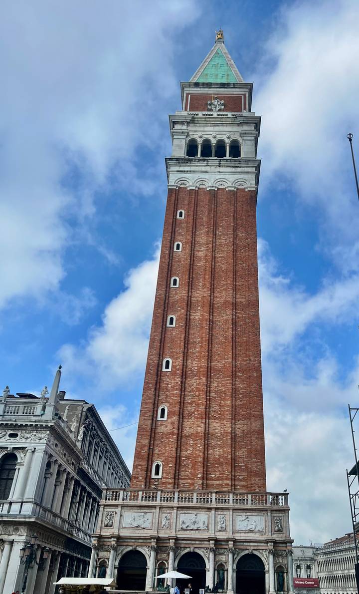 Tall red brick Campanile di San Marco soaring into partly cloudy sky