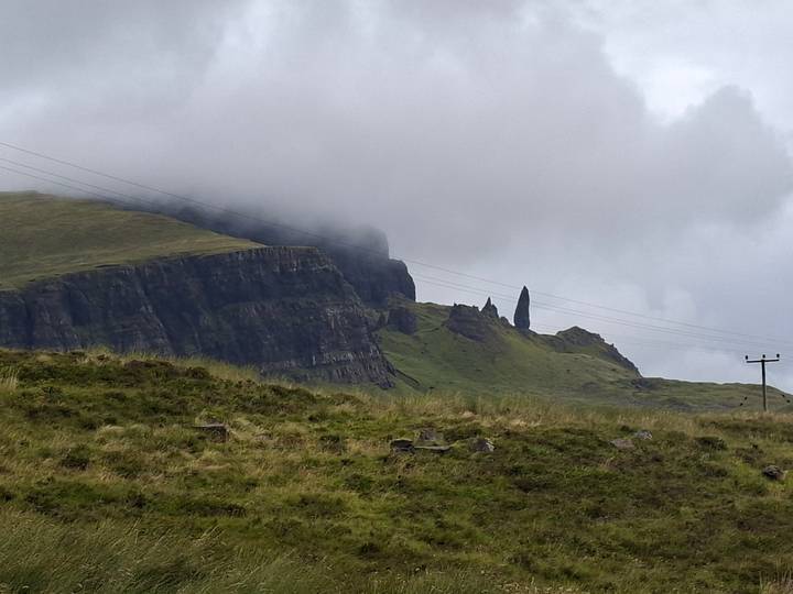 Moody view of the Old Man of Storr rock pinnacle emerging from misty cliffs