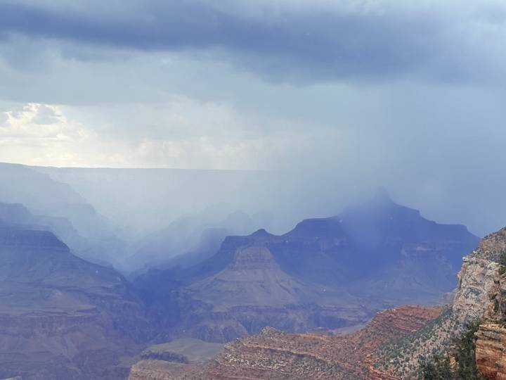 Grand Canyon layers fading into mist with a rainstorm sweeping across the cliffs