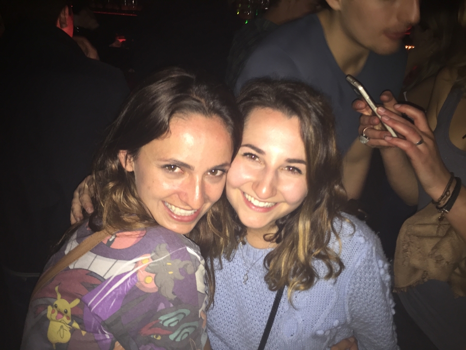 Two women smiling at an indoor social event.