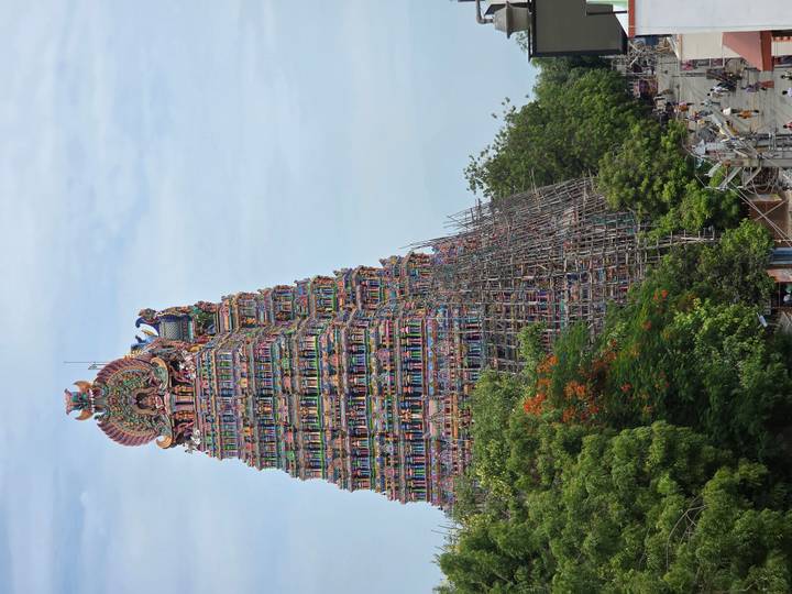 Vibrantly painted towering gopuram of Meenakshi style temple surrounded by scaffolding.
