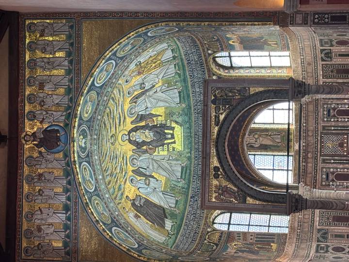Glittering Byzantine-style mosaic dome depicting saints inside a historic basilica.