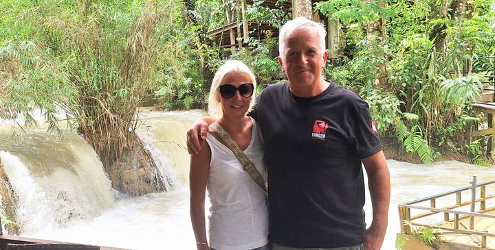 Couple posing together beside a cascading jungle waterfall.
