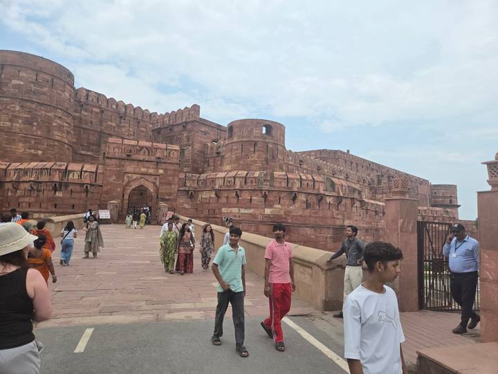 Visitors walk up the stone ramp toward the massive red sandstone walls of Agra Fort.
