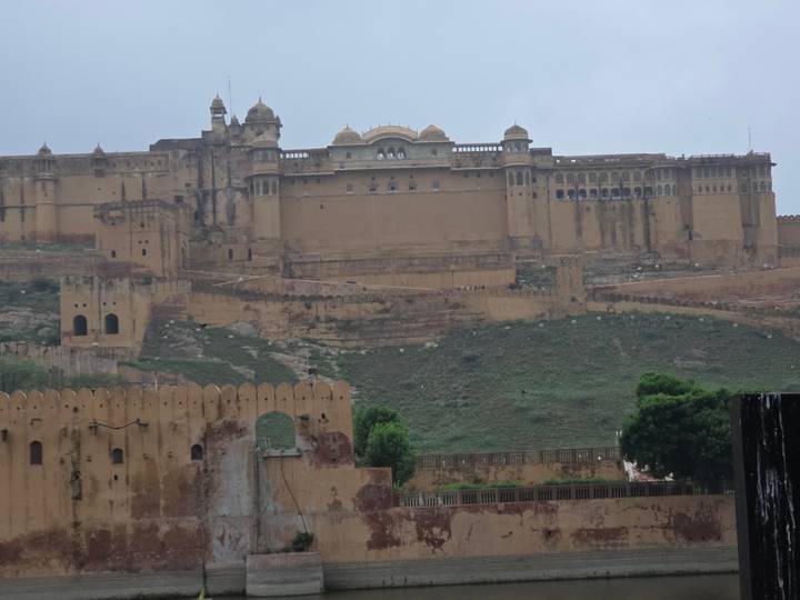 Expansive view of Amber Fort’s massive tan walls perched on a hillside in monsoon haze.