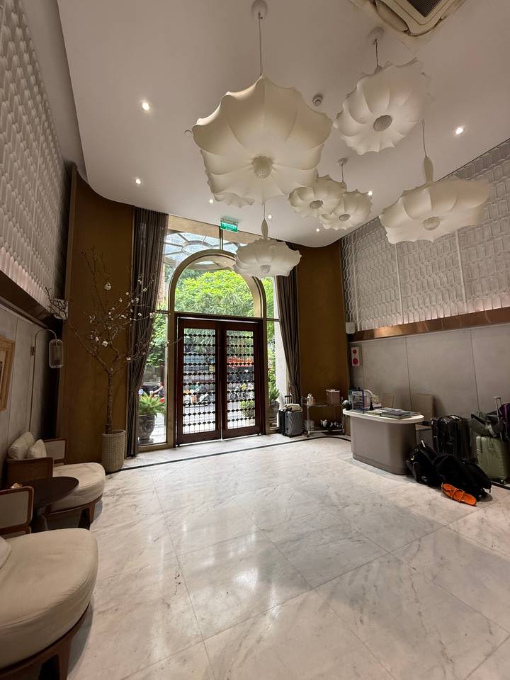 Chic hotel lobby with high ceiling, modern chandeliers, and luggage near the reception desk