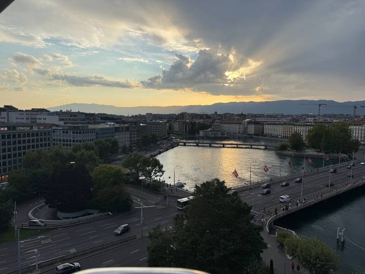 Aerial view of Geneva cityscape and lake at dusk with dramatic clouds and sun rays
