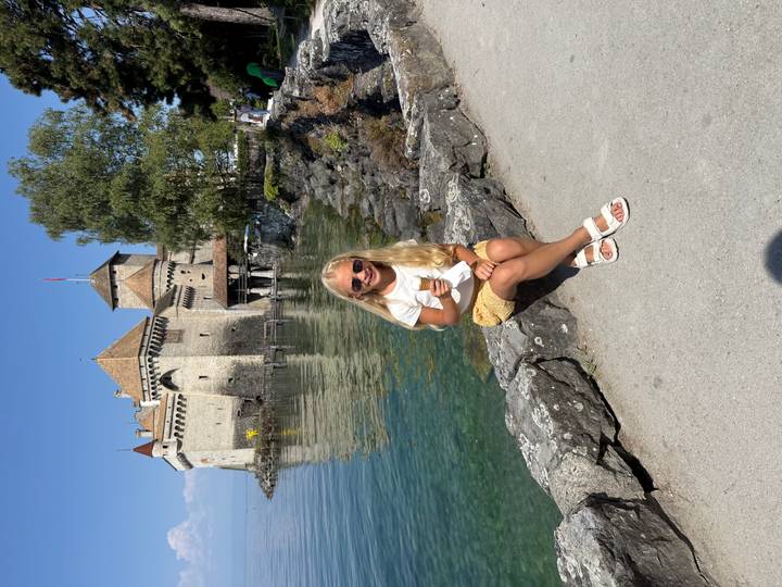 Girl eating ice cream in front of Chillon Castle with crystal clear lake reflections