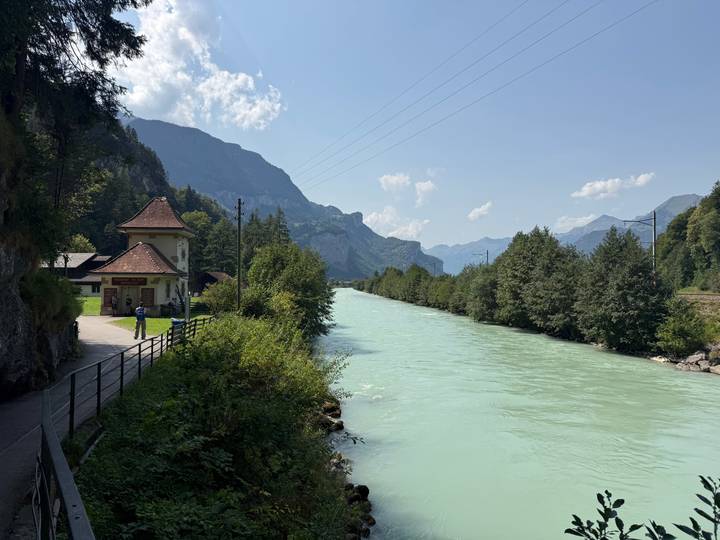 Milky turquoise river flowing through a lush Swiss valley with mountains in the distance