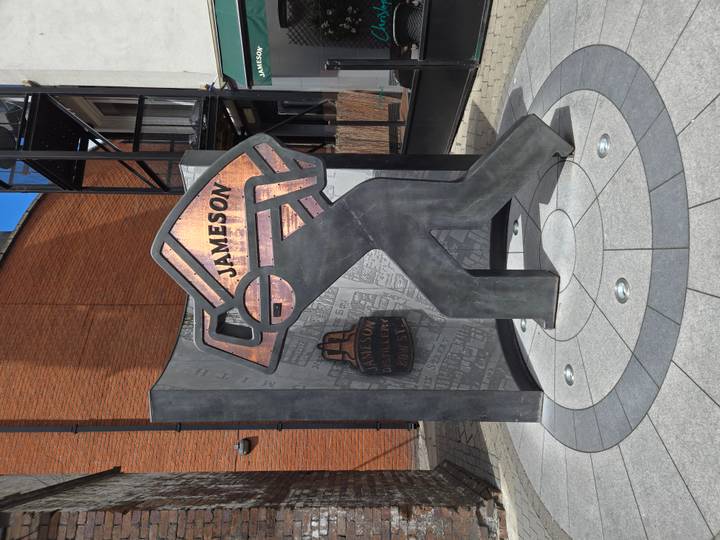 Modern metal sculpture and wall celebrating Jameson Whiskey outside the distillery in Dublin.