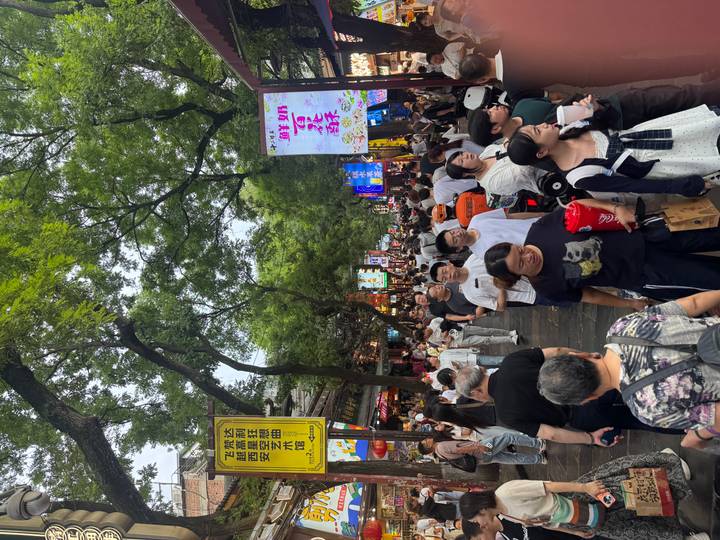 Crowded Muslim Street night market in Xi'an with neon signs and food vendors.