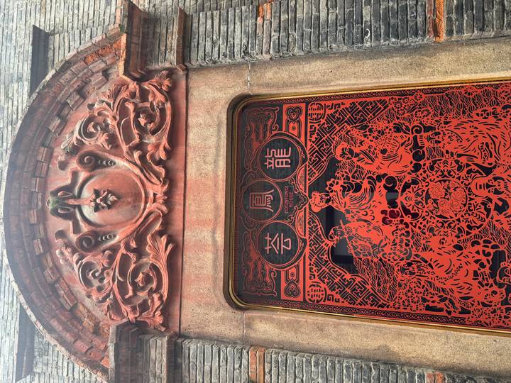 Decorative red carved window panel with traditional Chinese phoenix and dragon motifs.