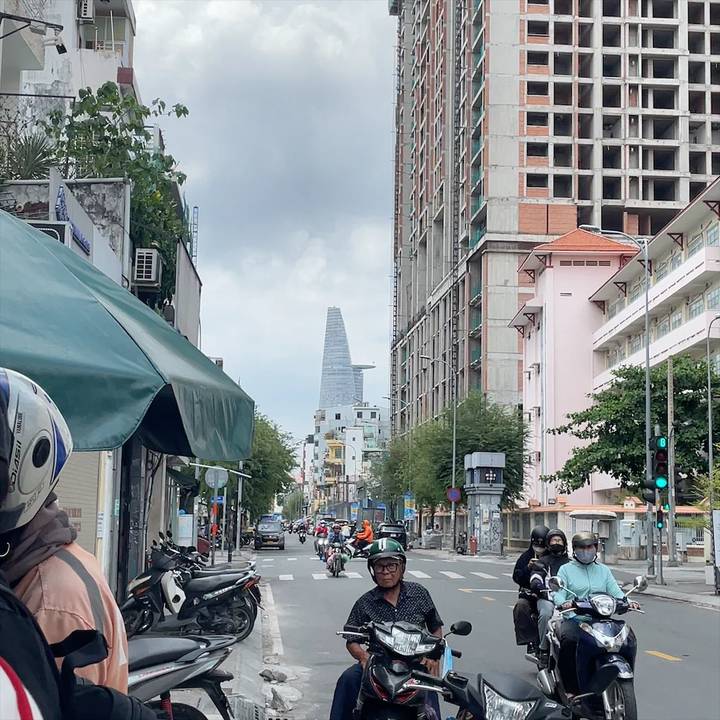 Busy Ho Chi Minh City street framed by tall buildings with the Bitexco Financial Tower visible ahead.