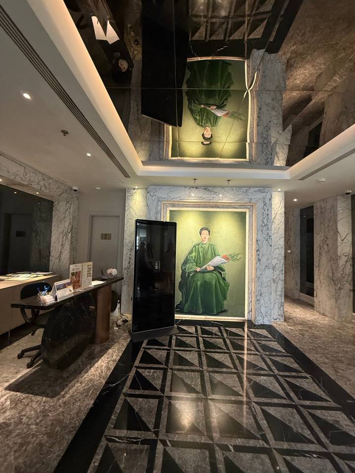 Marble-clad hotel lobby featuring a large portrait of a woman in green traditional dress.