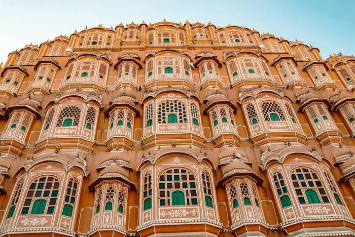 Symmetrical façade of Jaipur's Hawa Mahal with rows of latticed windows glowing in warm light.