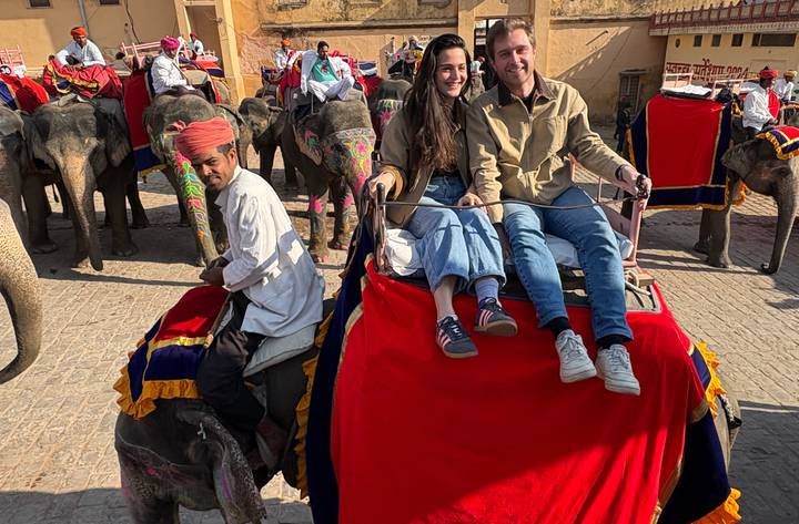 Tourists ride atop an elephant draped in red cloth among many others lined up near Amber Fort.