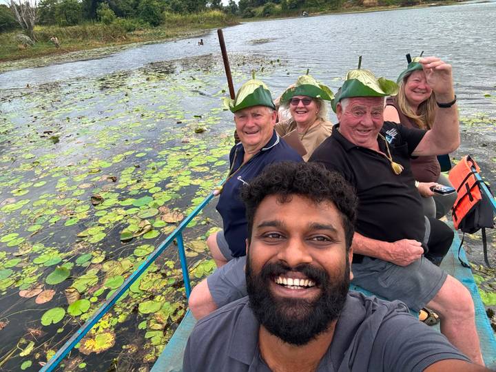 Boat selfie of travellers wearing playful leaf hats gliding over lily-covered lake
