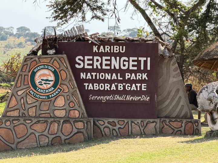Entrance sign reading 'Karibu Serengeti National Park' with a person standing nearby.