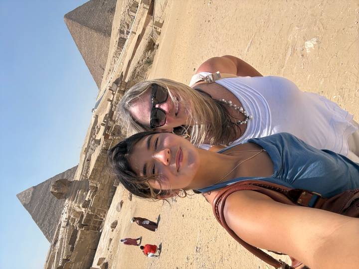 Wind-swept mother and daughter selfie with the Sphinx and a pyramid in the bright desert sun