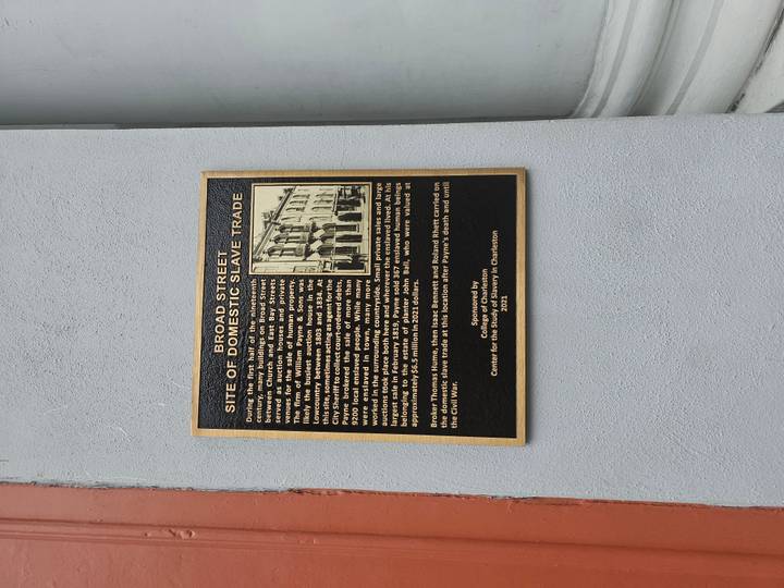 Historical plaque on a wall detailing the site of domestic slave trade on Broad Street in Charleston
