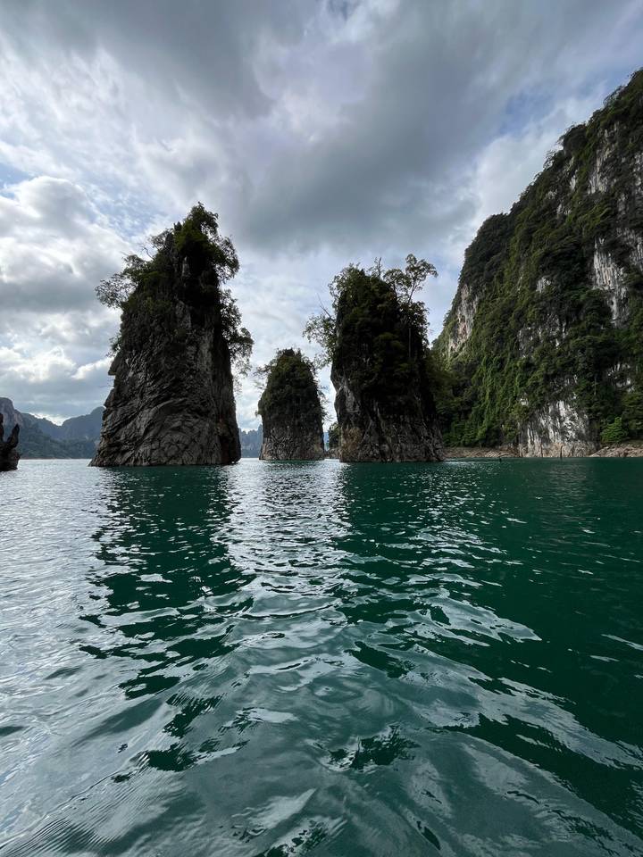 Towering limestone karst pillars rise from emerald water in Khao Sok National Park