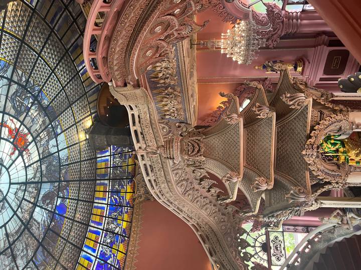 Intricately decorated pink interior of the Erawan Museum with carved staircases and stained-glass dome
