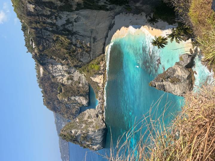 Panoramic view of dramatic limestone cliffs surrounding a turquoise cove and white-sand beach.
