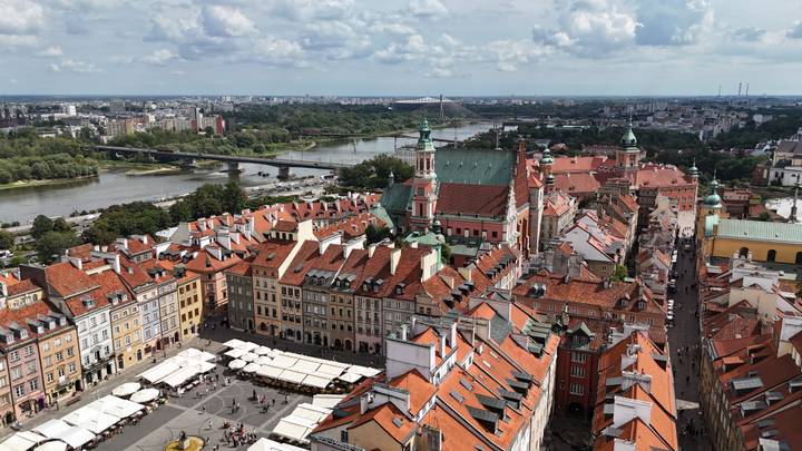 panoramic aerial of Warsaw Old Town with red tiled roofs, central church and winding river