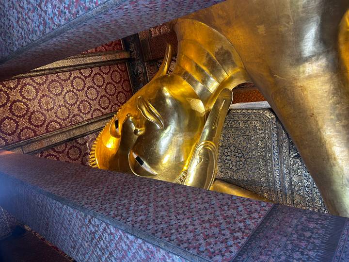 Close interior angle of the gilded reclining Buddha surrounded by decorative patterned walls