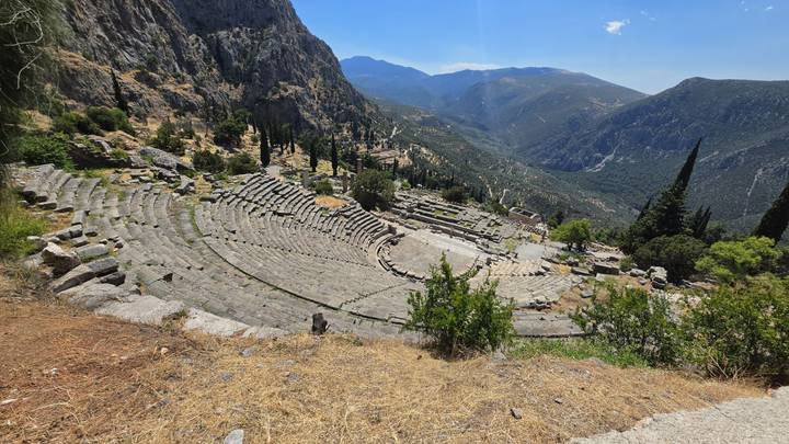 High vantage of Delphi’s ancient theatre nestled on a mountainside overlooking a deep valley.