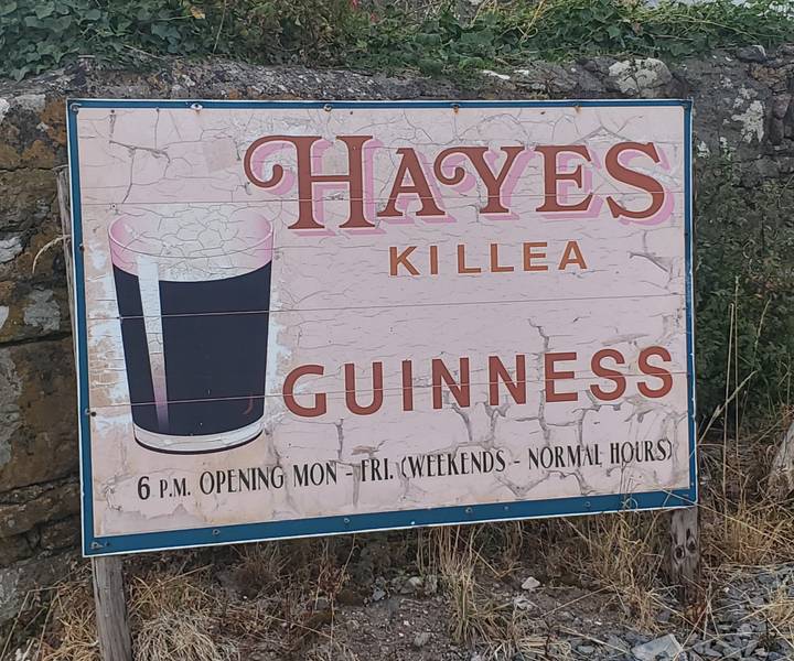 Weathered pub sign advertising Guinness with a pint graphic and vintage lettering on a cracked pink background