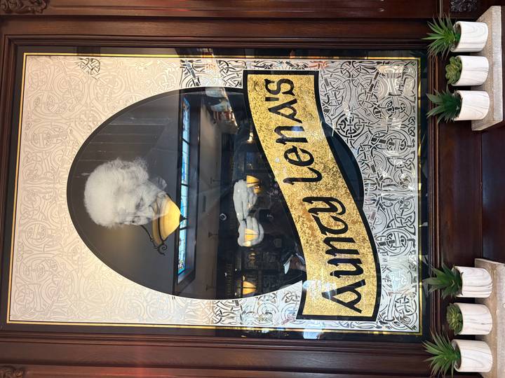 Decorative pub sign featuring an elderly woman's portrait and the text 'Aunty Lena's' in Celtic style